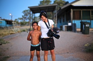 Young Indigenous boy next to film director in remote community.