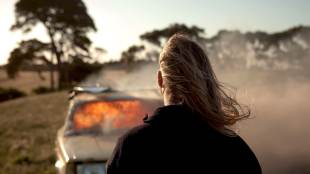 Boy watches burning car