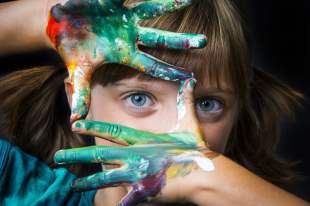 Little girl framing face with painted fingers