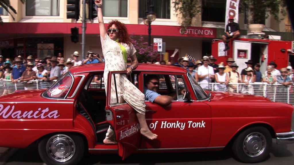 Wanita leans out of car waving on parade