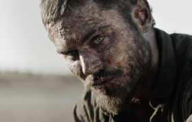 A bearded man (Zac Efron) with a muddy face