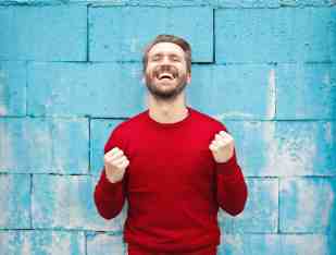 a man in front of a blue wall celebrating a win.