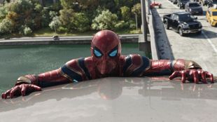 spider-Man holds onto car roof over lake.