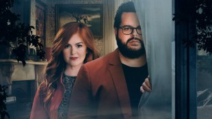 Actors Isla Fisher and Josh Gad look at the viewer from behind a curtain in a publicity shot for Wolf Like Me.