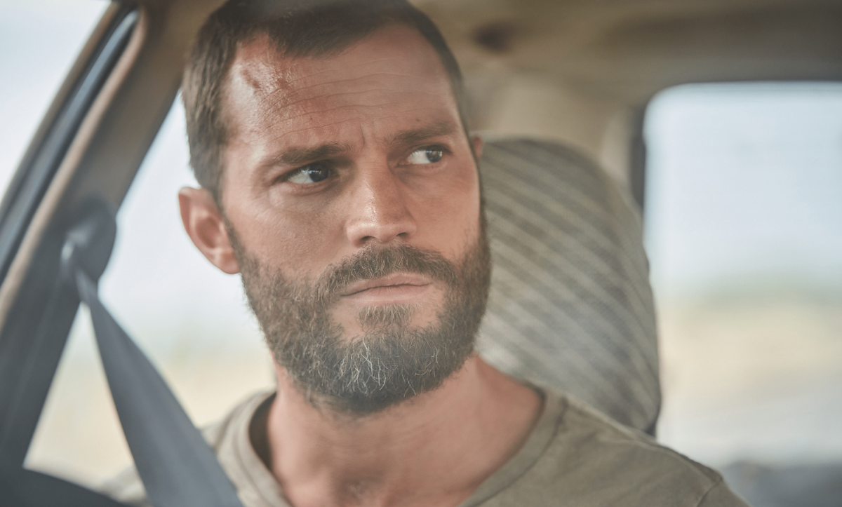A man with a grubby appearance sits in the driver's seat of a car