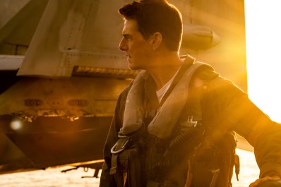 A man (Tom Cruise) in profile agains the backdrop of a fighter jet