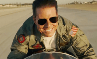 Top Gun: Maverick Tom Cruise on a motorbike looking happy