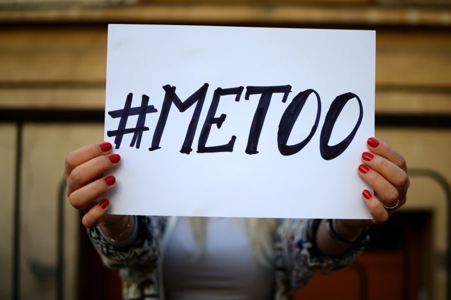 a woman's hands holding a sign saying #MeToo in bold letters