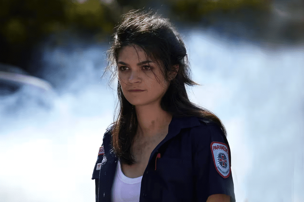 Actress Tahlee Fereday as character Cate, a woman with brunette hair wearing a paramedic's uniform.