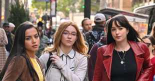 Three women stand in a busy street looking out in the direction of the viewer.