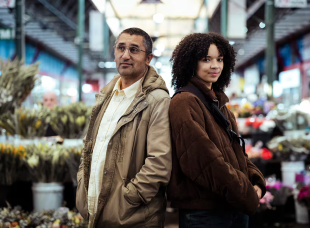 A father and daughter in a market look at the camera in a publicity shot for the new Australian crime series Swift Street on SBS.