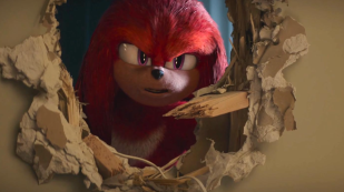 Knuckles the Echidna looks menacingly through a hole in a wall in a publicity still for the animated series Knuckles on Paramount+.
