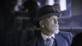 The actor John Malkovich, playing Inspector Poirot, is sitting on a train looking out of the window in a publicity still for Agatha Christie: The ABC Murders on BritBox.