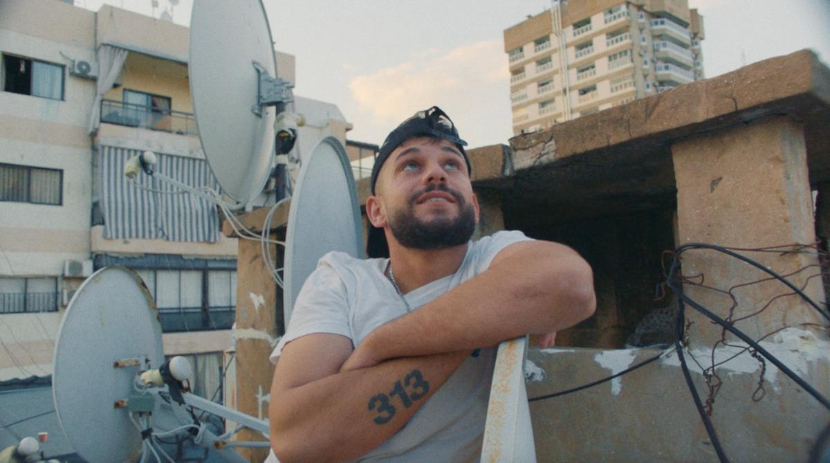 A Young Bearded Man On A Rooftop Looks Into The Sky In A Still From The Documentary Kash Kash On Docplay.