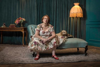 Dr Jeni Haynes lives with dissociative identity disorder, and is the subject of the compelling new SBS-screened documentary We Are Jeni. A middle-aged woman wearing a floral dress and glasses sits on a chaise lounge next to a small brown dog.